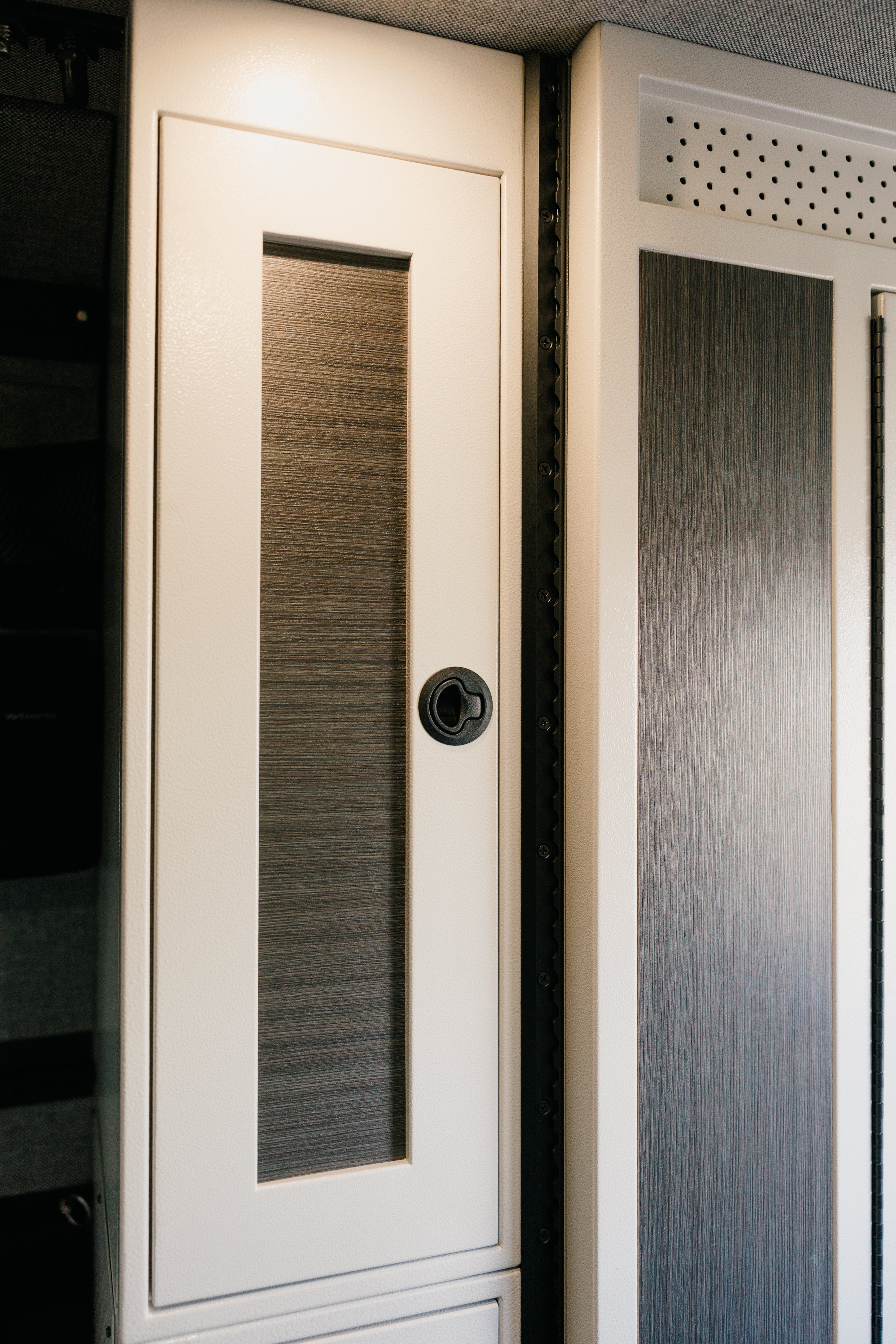 White 12-inch wide vertical aluminum upper van closet showing a single shaker-style door with flush slam latch installed in van