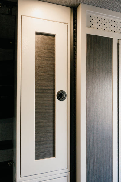 White 12-inch wide vertical aluminum upper van closet showing a single shaker-style door with flush slam latch installed in van