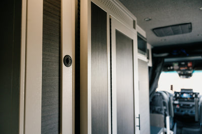 White 12-inch wide vertical aluminum upper van closet showing a single shaker-style door with flush slam latch installed in van
