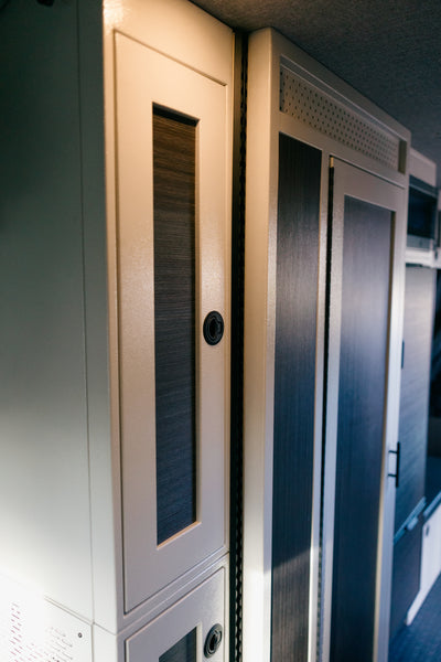 White 12-inch wide vertical aluminum upper van closet showing a single shaker-style door with flush slam latch installed in van